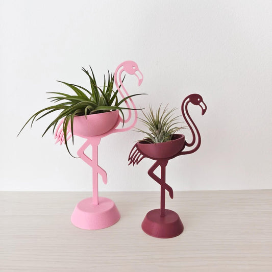 Two flamingo air plant holders side by side, styled as decorative plant displays