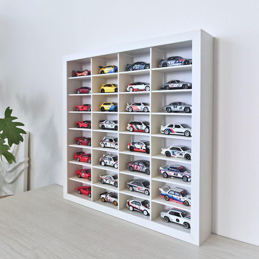Angled view of the white SANNAHED display frame filled with 32 miniature diecast cars, showing the depth of the compartments.