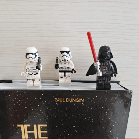Minifigure bookmark clips attached to the top of a book with three brick-style figures