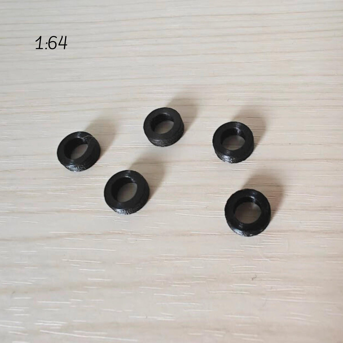 Multiple 1:64 scale miniature tires arranged individually on surface for display