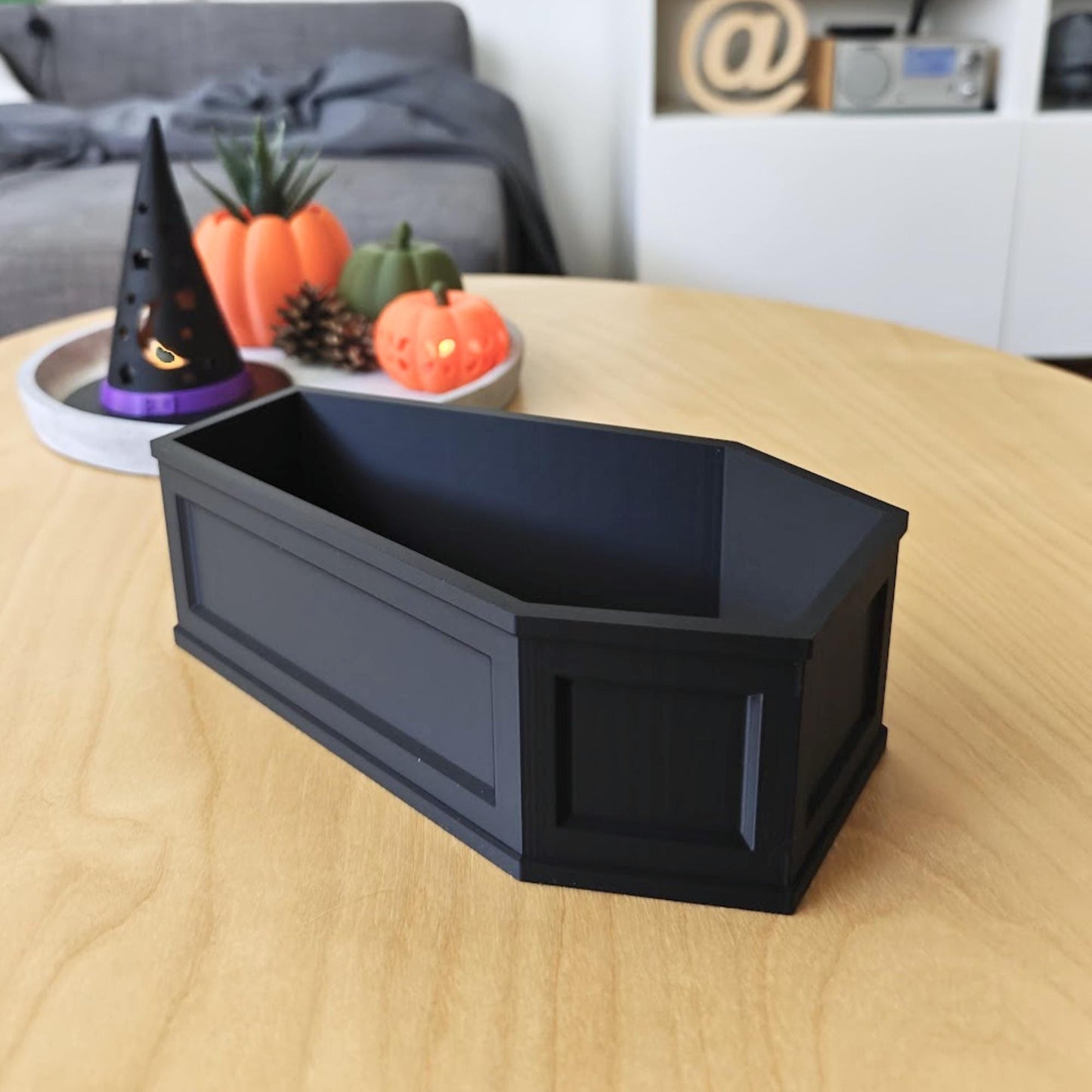 Side view of the coffin dish on a wooden table, showing its gothic-style panel details and sturdy walls.