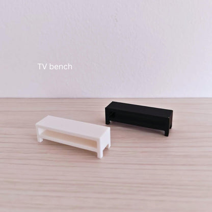 Small-scale modern TV benches in white and black, displayed on a light wood surface.