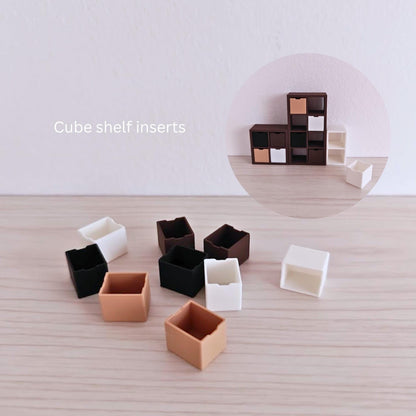 Close-up of 3D-printed cube shelf inserts in neutral and dark colors, suitable for miniature shelving units.