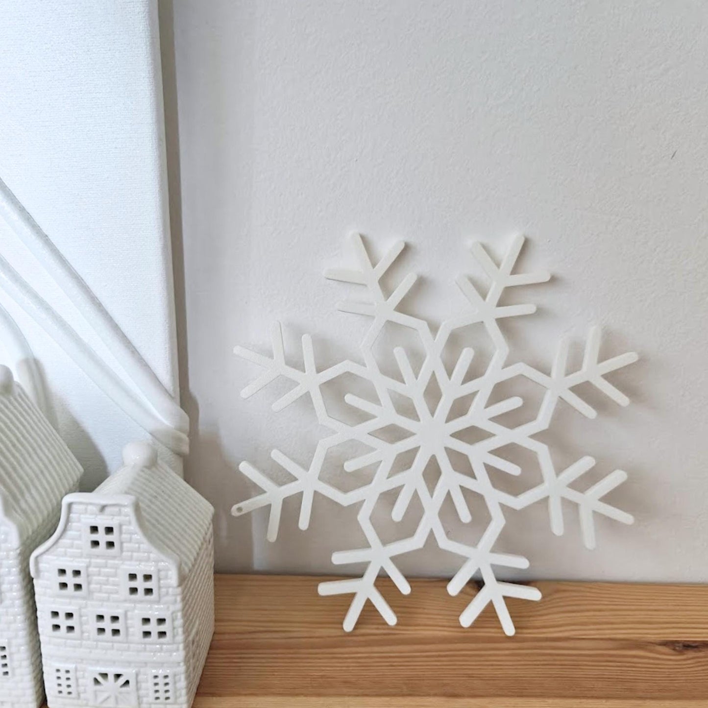 Close-up of a white 3D-printed snowflake ornament placed on a wooden surface.