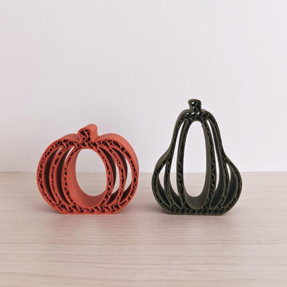 Orange and green 3D-printed pumpkins and gourds displayed together on a neutral background.