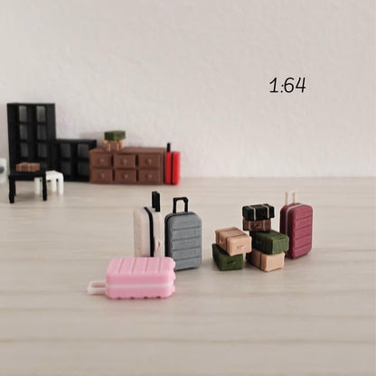 Miniature luggage arranged in a small 1:64 diorama scene with furniture such as tables and cabinets, placed on a light background.