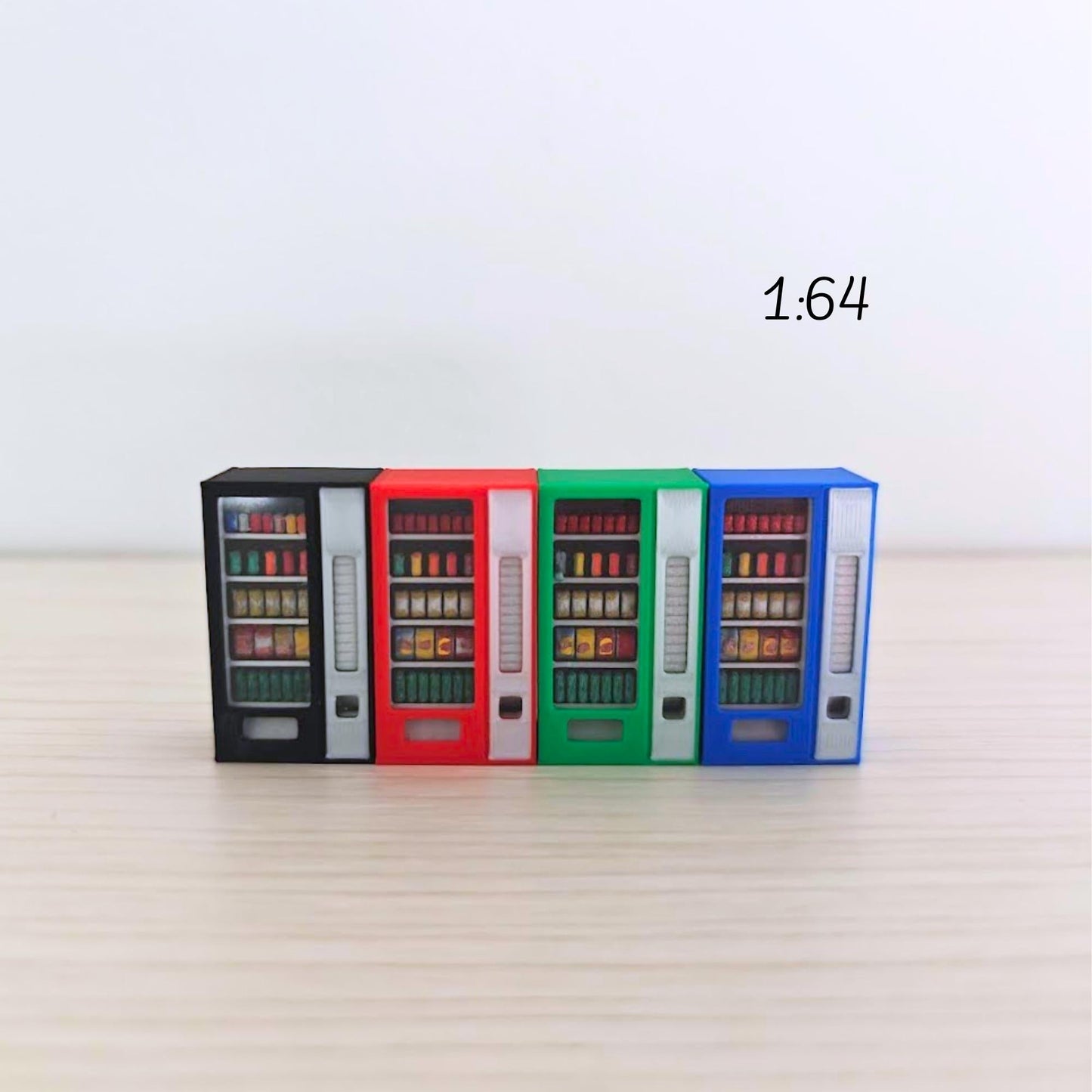 Four 1:64 scale miniature vending machines in blue, green, red, and black arranged in a row on a light wooden background. Each has visible painted snacks and drinks behind clear plastic panels.