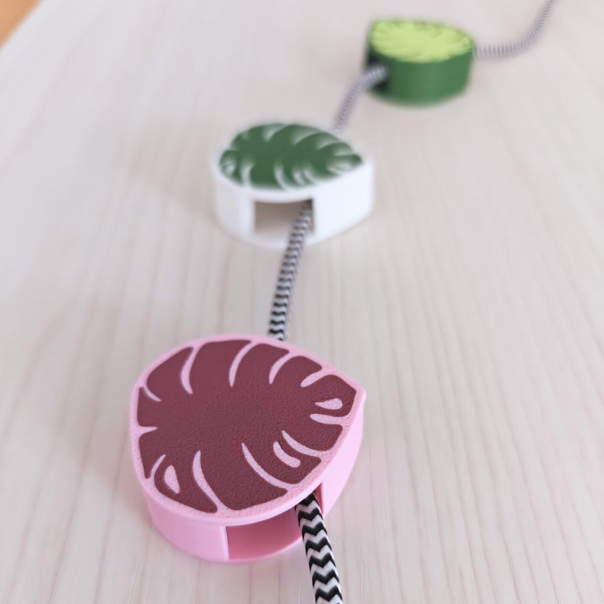 Close-up of pink monstera cable clip attached to a braided cable