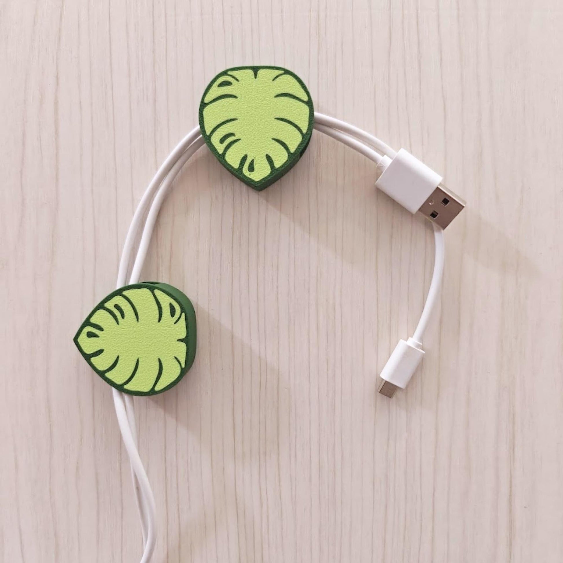 Green monstera cable clips organizing multiple cords