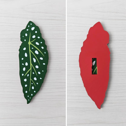 Front and back view of a Begonia leaf handle, showing the spotted green leaf front and red back with key slot opening.