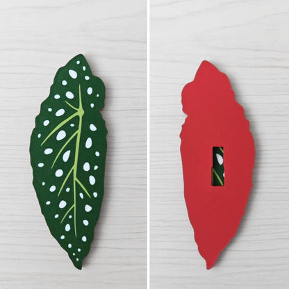 Front and back view of a Begonia leaf handle, showing the spotted green leaf front and red back with key slot opening.
