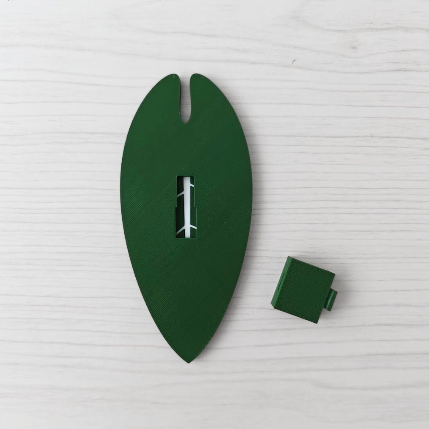 Back view of the handle with the separate green cover piece placed beside it.