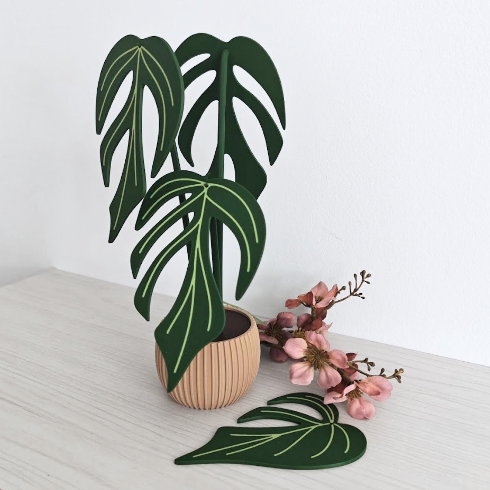 Angled view of the Monstera Burle Marx Flame coaster set in a wooden holder, with one coaster leaning in front.