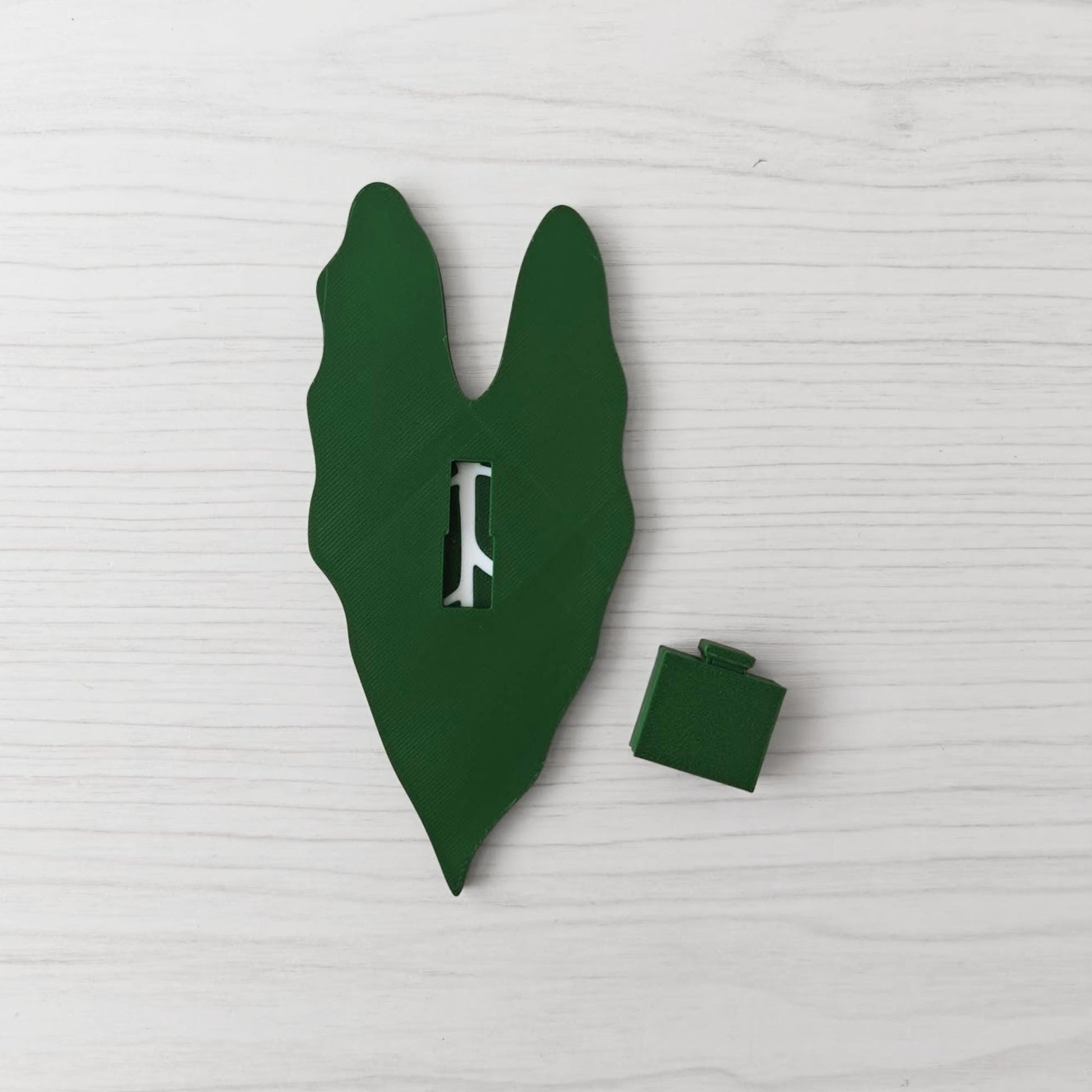 Back view of the handle showing the key slot opening, with the separate green cover piece placed beside it.