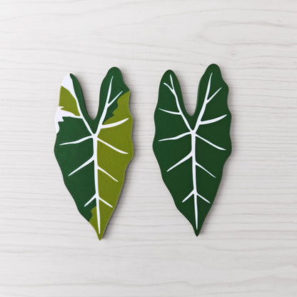 Front view of two Alocasia Frydek key cover handles for IKEA FABRIKÖR, shown in solid green and green with white variegation on a light wood background.