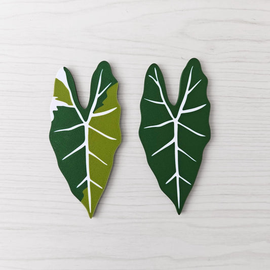 Front view of two Alocasia Frydek key cover handles for IKEA FABRIKÖR, shown in solid green and green with white variegation on a light wood background.