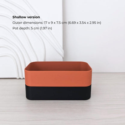 Shallow rectangular self-watering planter assembled in terracotta and black.