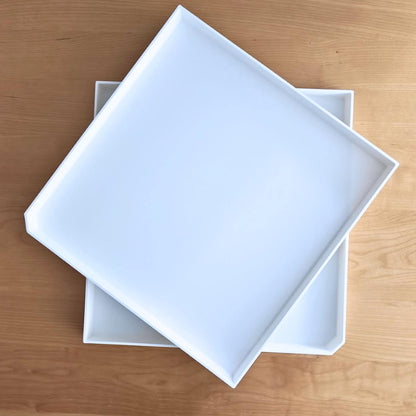 Two drainage trays stacked on wooden surface