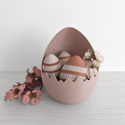 Cracked eggshell Easter basket holding decorative eggs and flowers on a neutral surface