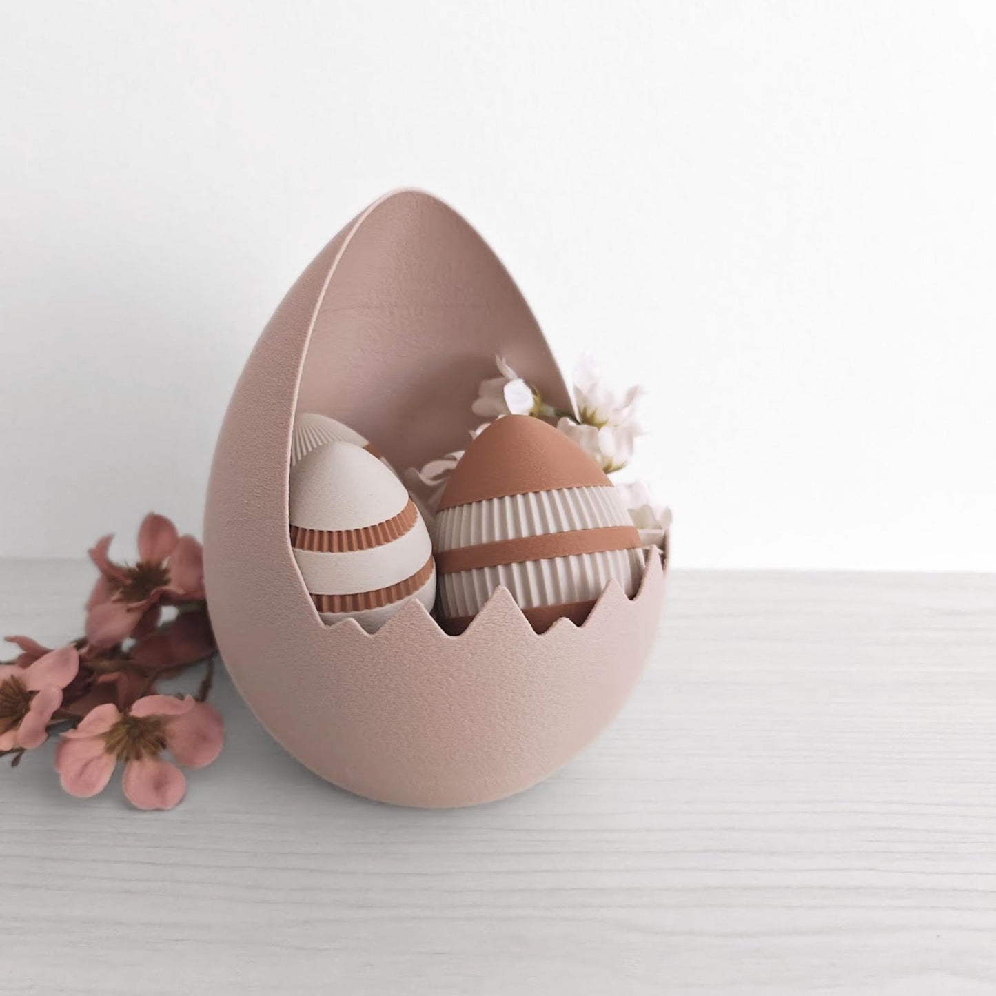 Cracked eggshell Easter basket filled with textured eggs and soft pink flowers