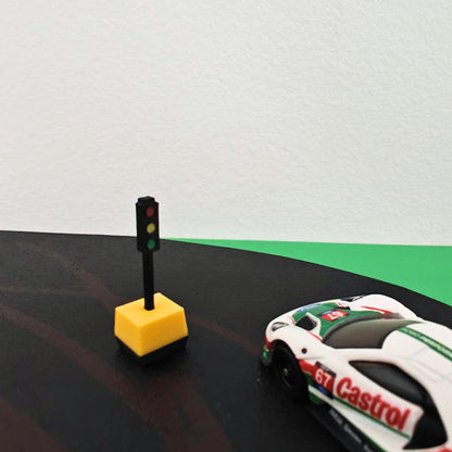 Single 1/64 portable traffic light with yellow base beside diecast car