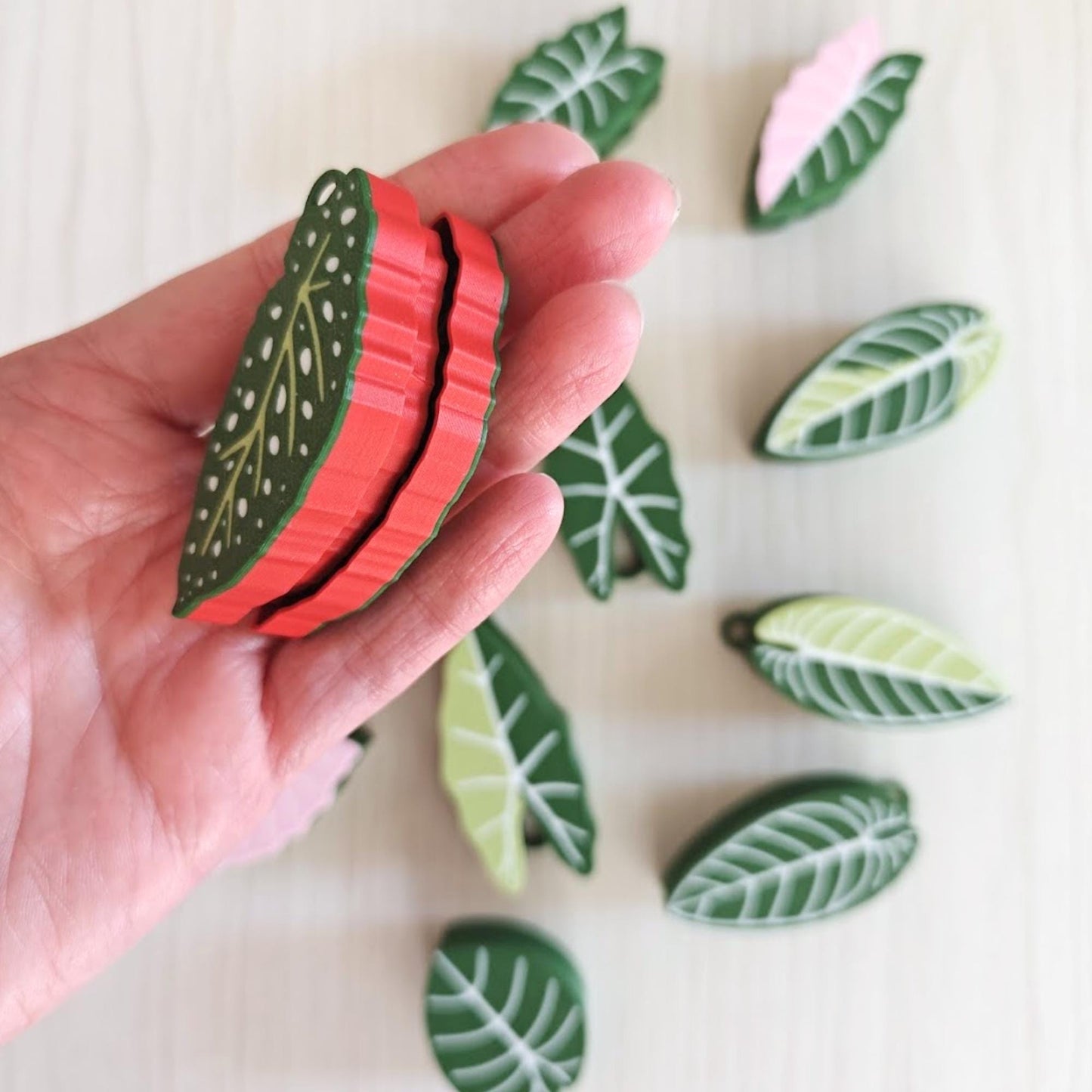 Hand holding double-sided leaf clicker showing layered design