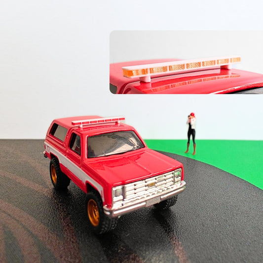 Red 1:64 scale SUV model with roof light bar installed in diorama scene