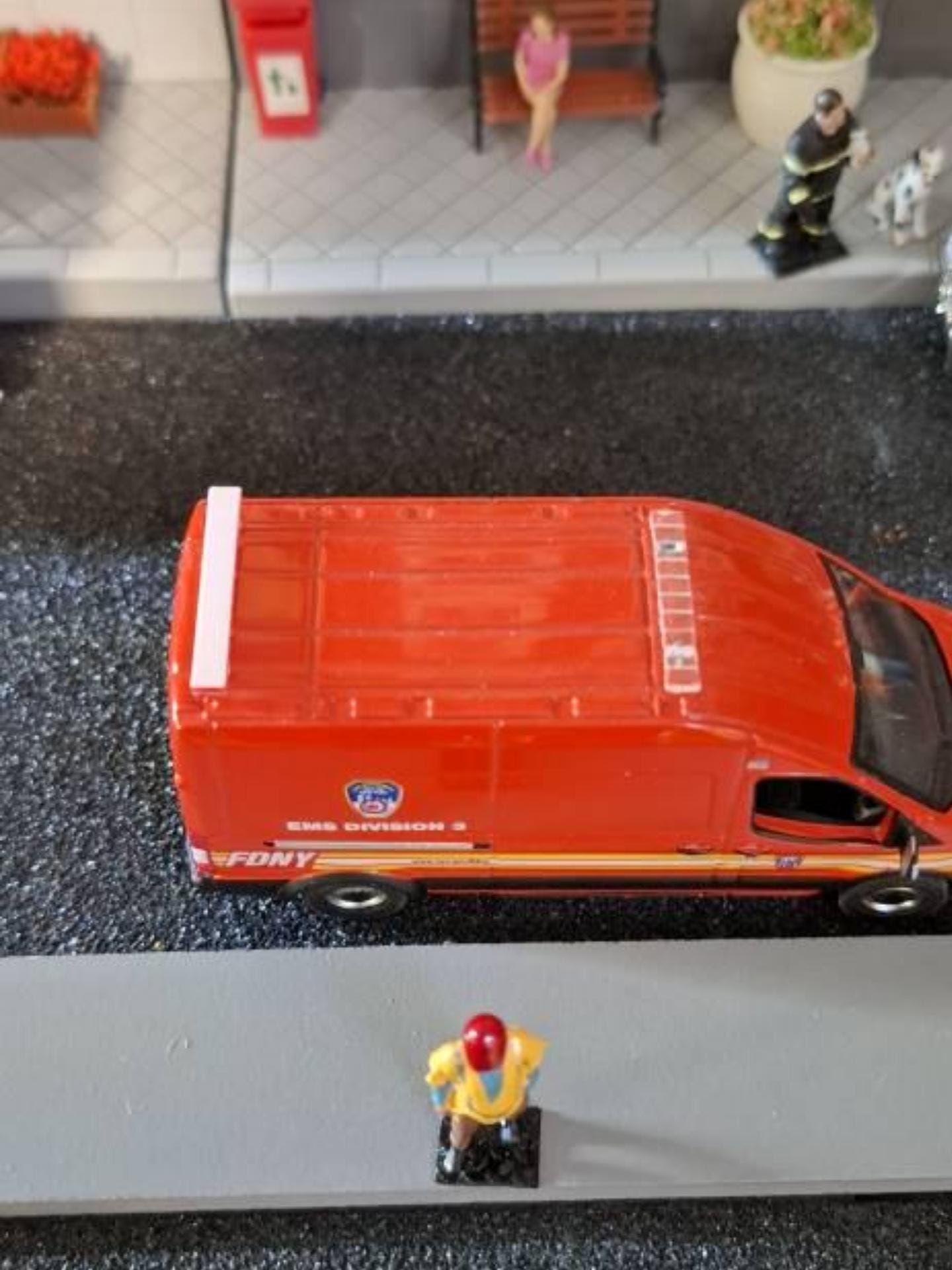Orange van model with roof light bar driving on textured diorama surface