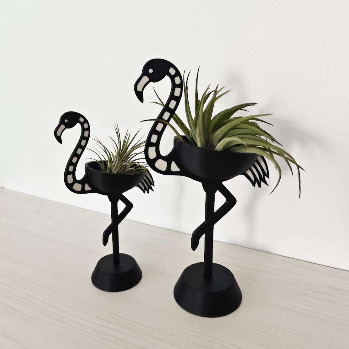 Pair of skeleton flamingo Tillandsia holders shown at an angle, highlighting size difference