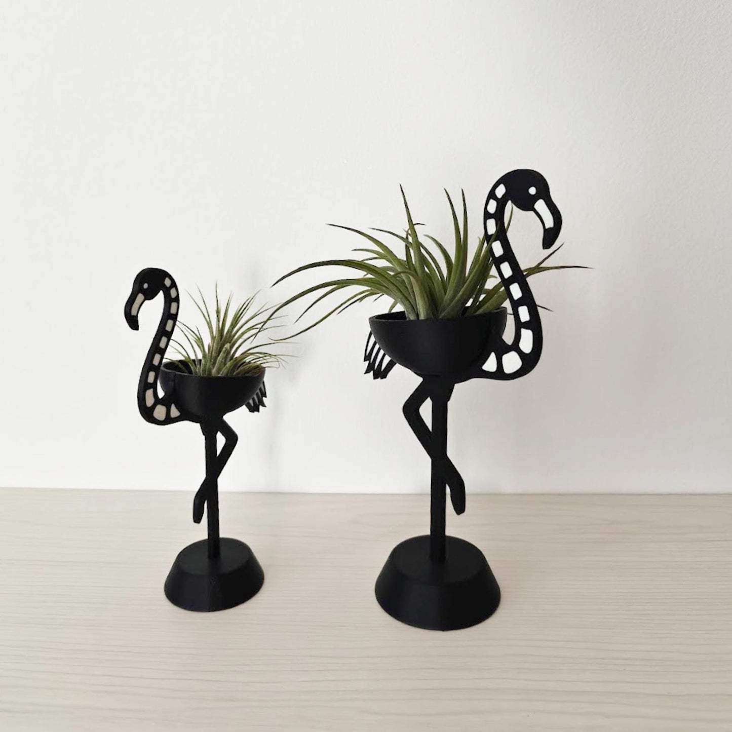 Pair of skeleton flamingo Tillandsia holders shown at an angle, highlighting size difference