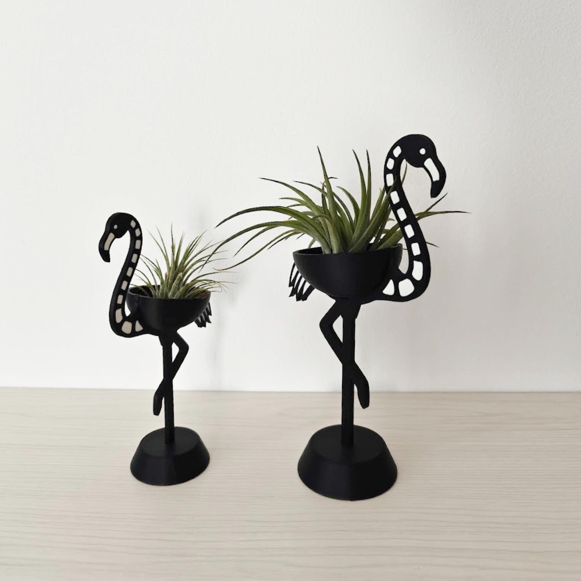 Pair of skeleton flamingo Tillandsia holders shown at an angle, highlighting size difference