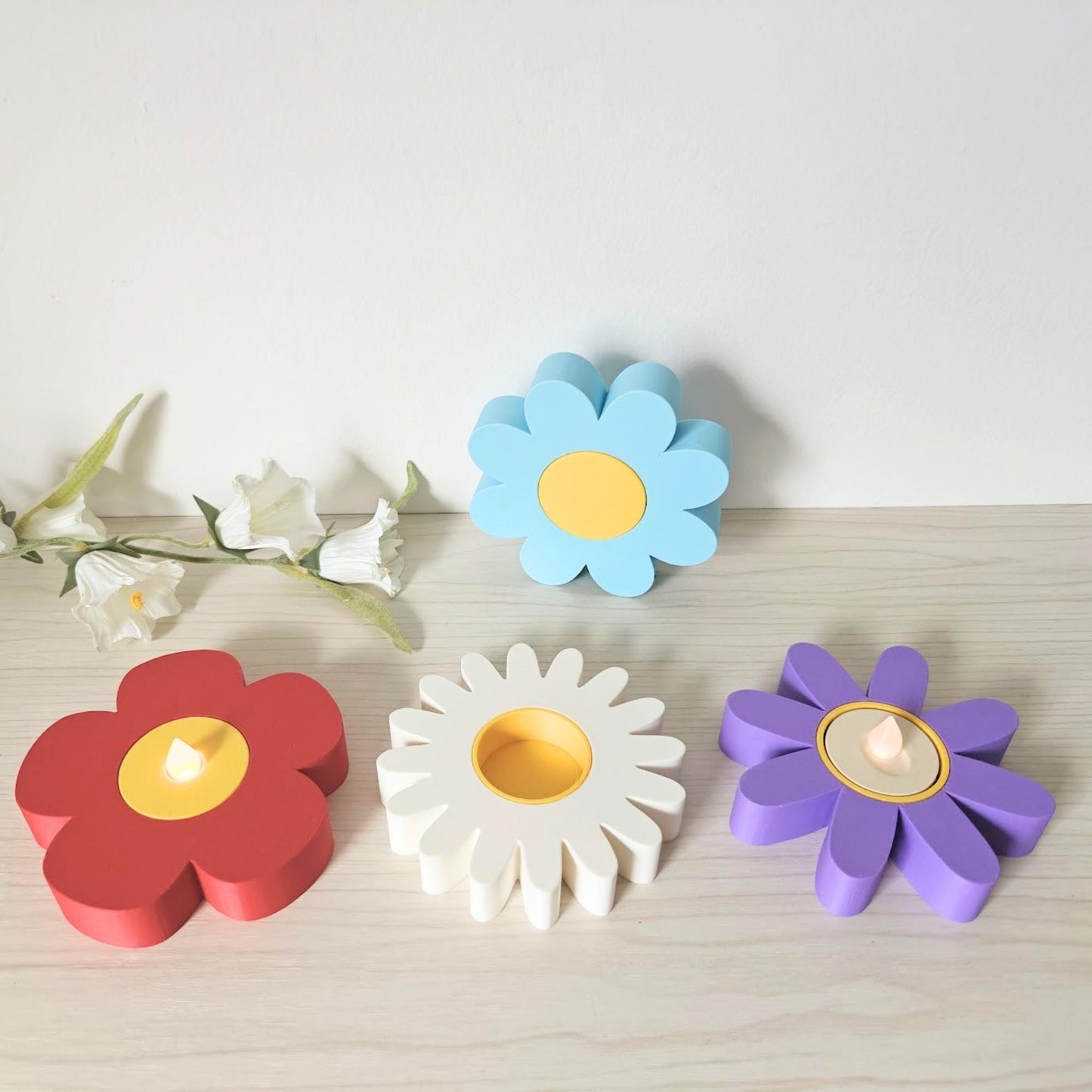 Group of flower tealight holders arranged on a shelf with flowers