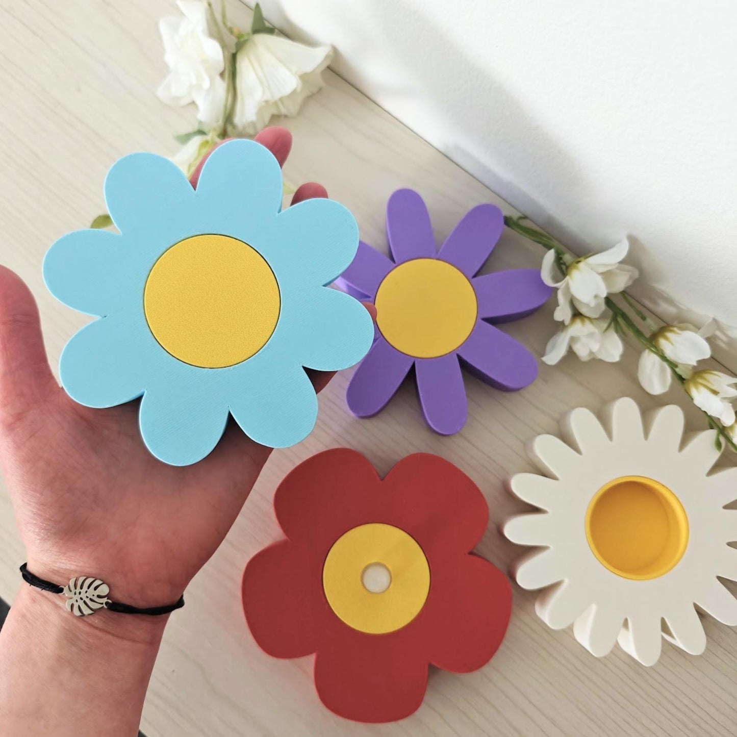 Hand holding multiple colorful flower tealight holders for scale