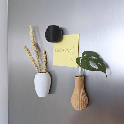 Three mini magnetic vases on a gray magnetic surface, holding dried wheat and a small green cutting.