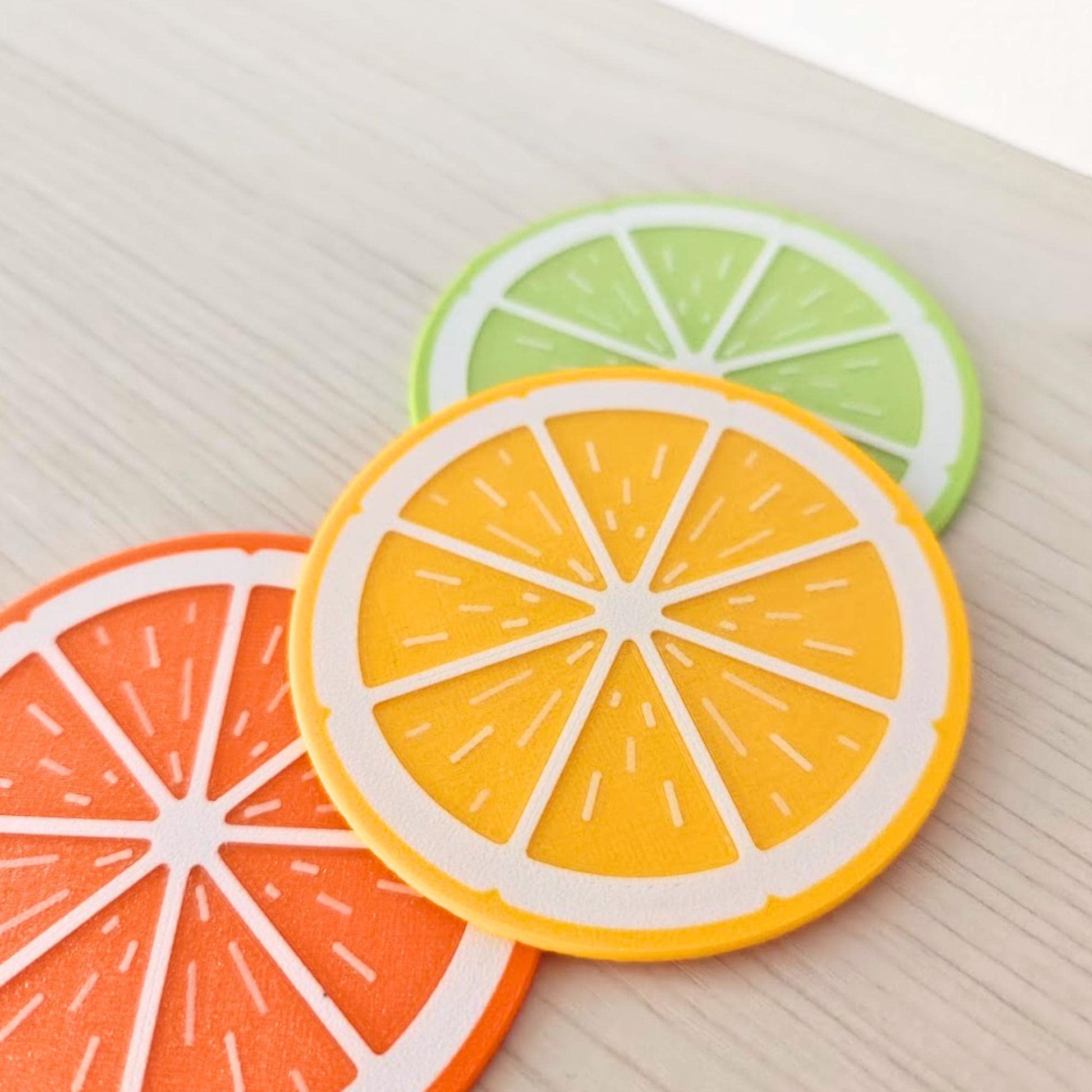 Close-up of colorful citrus slice coasters showing lemon, orange and lime designs.
