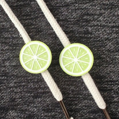 Lime green half-fruit drawstring charms on white hoodie cords, close-up view on dark gray fabric.