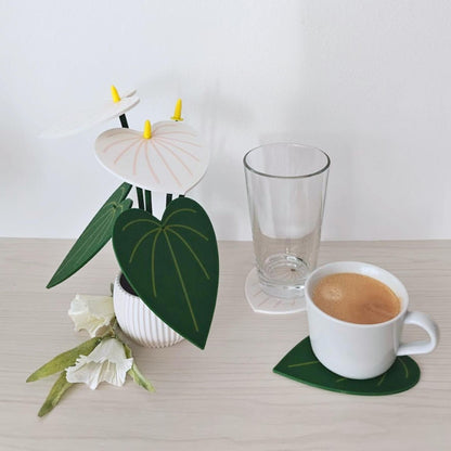 White Anthurium plant coaster set shown next to a glass and coffee cup to demonstrate coaster use.