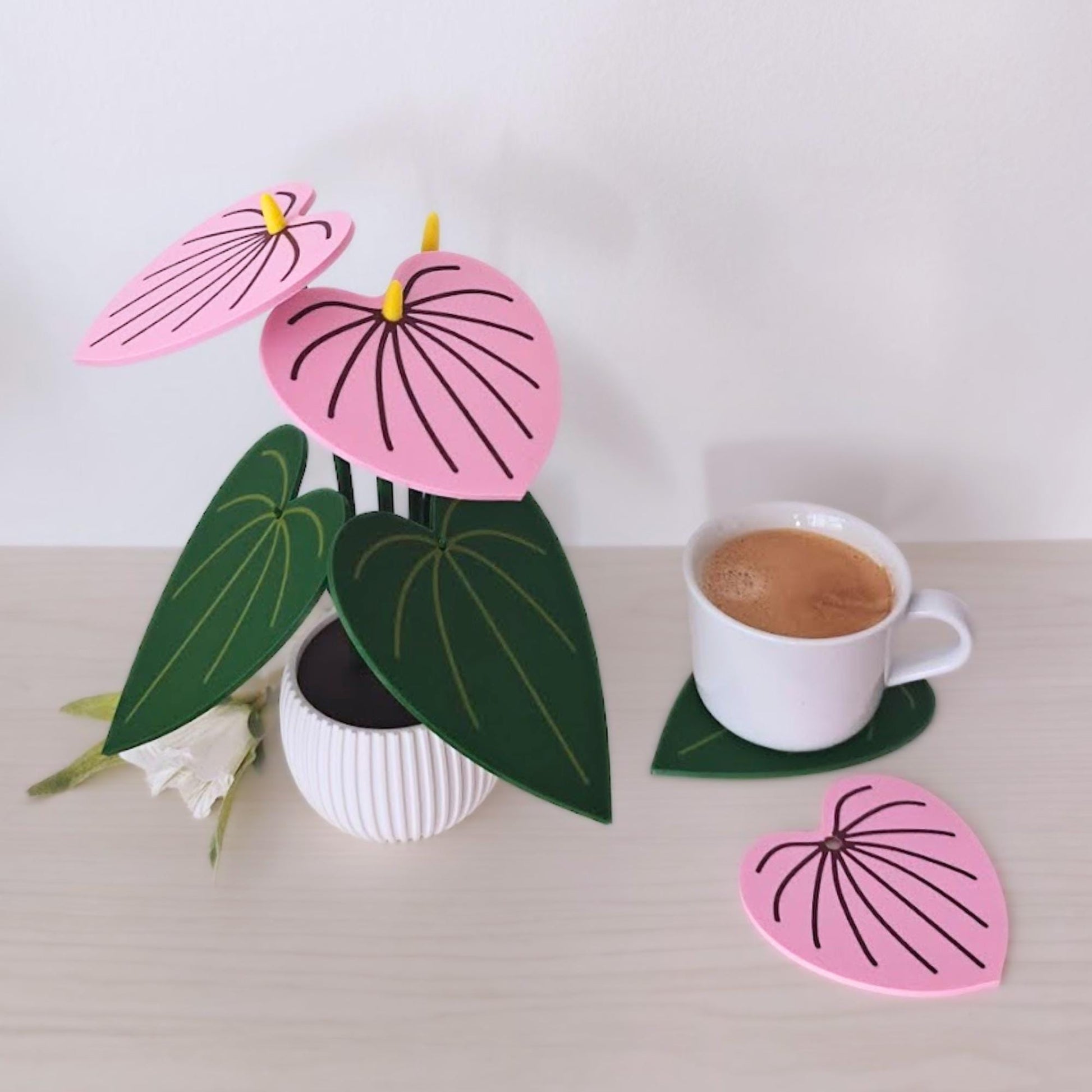 Pink Anthurium coaster set with one leaf coaster removed and placed beside a coffee cup.