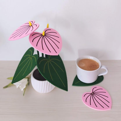Pink Anthurium coaster set with one leaf coaster removed and placed beside a coffee cup.