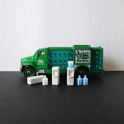1:64 scale miniature water dispenser set with blue water bottles displayed in front of a green diecast delivery truck.