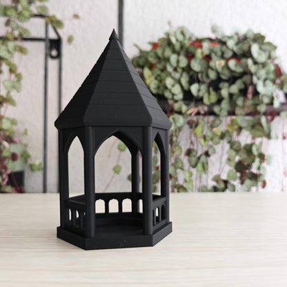 Empty Gazebo: A matte black gothic gazebo tealight holder sitting empty on a wooden surface.