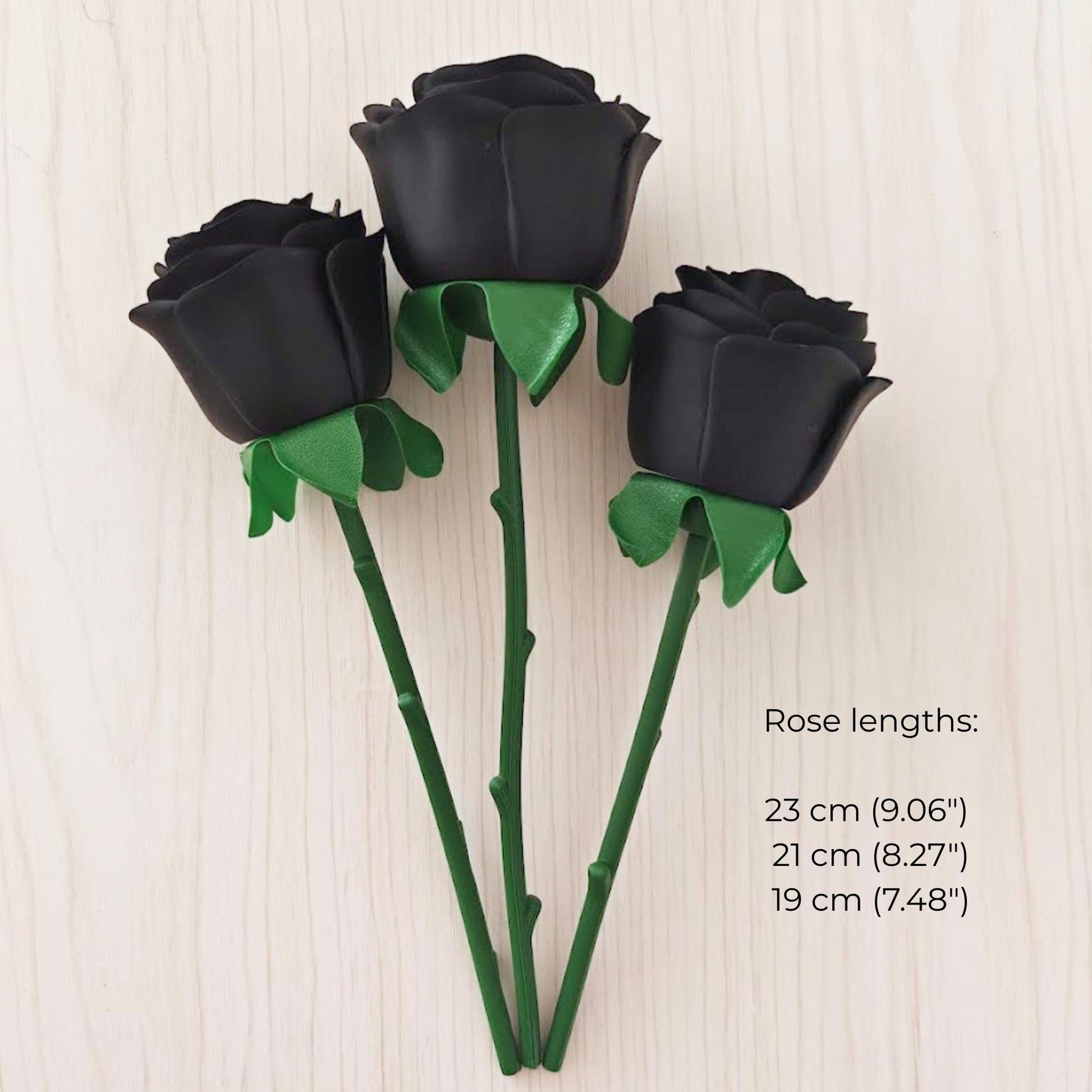 Three black faux roses with green stems in lengths of 19 cm, 21 cm and 23 cm.