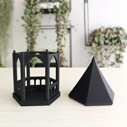 Detached Roof: A black gothic gazebo tealight holder with its pointed, tiered roof removed and placed next to the hexagonal arched base to show how to insert a tealight.