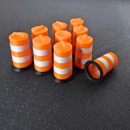 Close-up of miniature orange traffic barrels with metallic silver bands, including one barrel lying on its side.