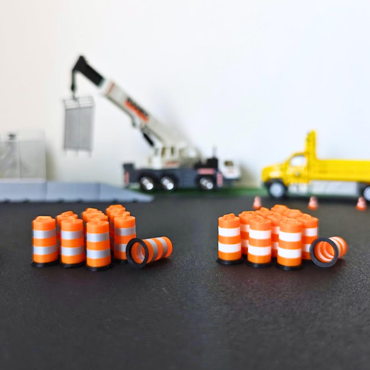 Miniature orange traffic barrels with white and metallic silver bands displayed in a 1:64 scale road construction diorama.