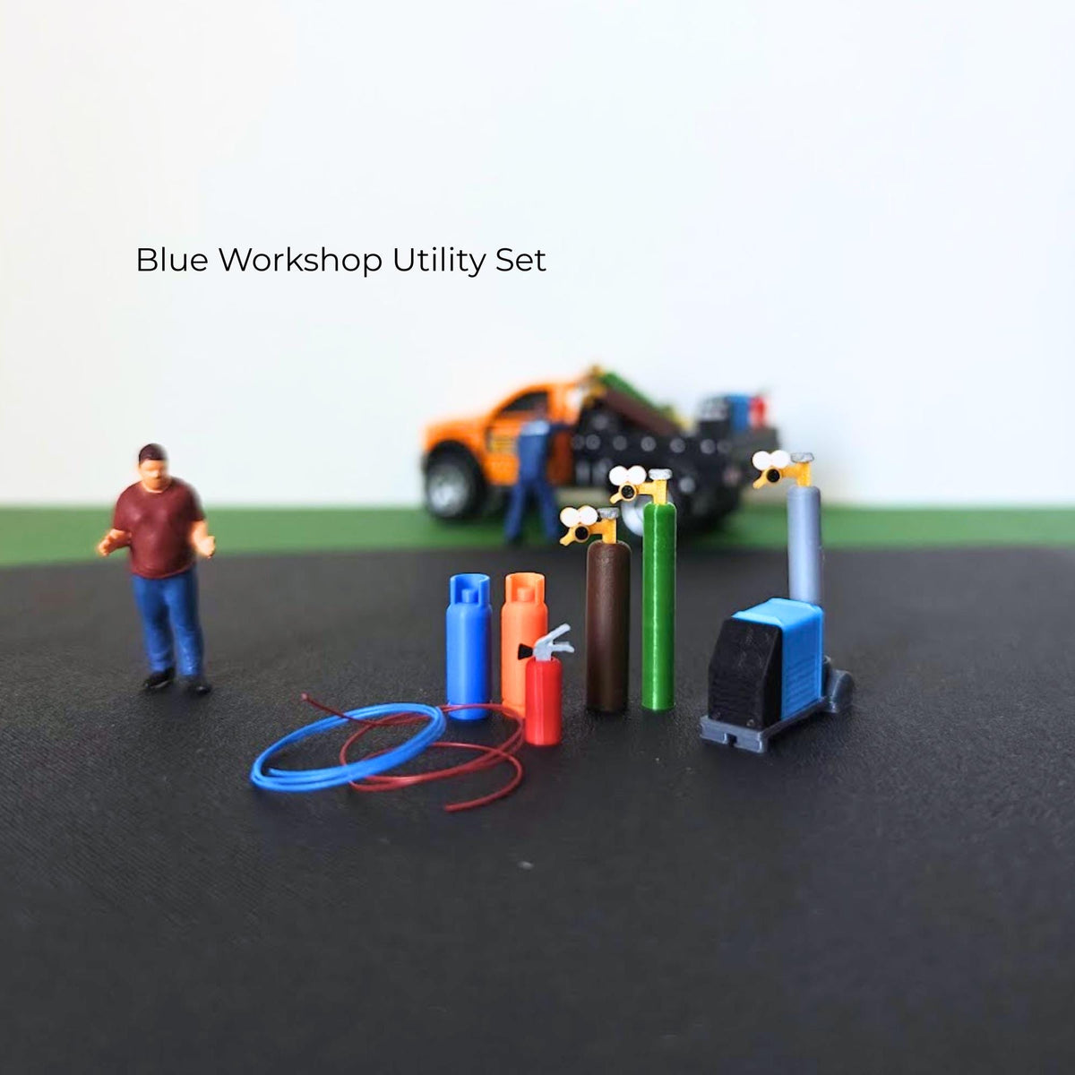 Blue workshop utility set with gas cylinders, welding machine, fire extinguisher and coiled red and blue hoses.