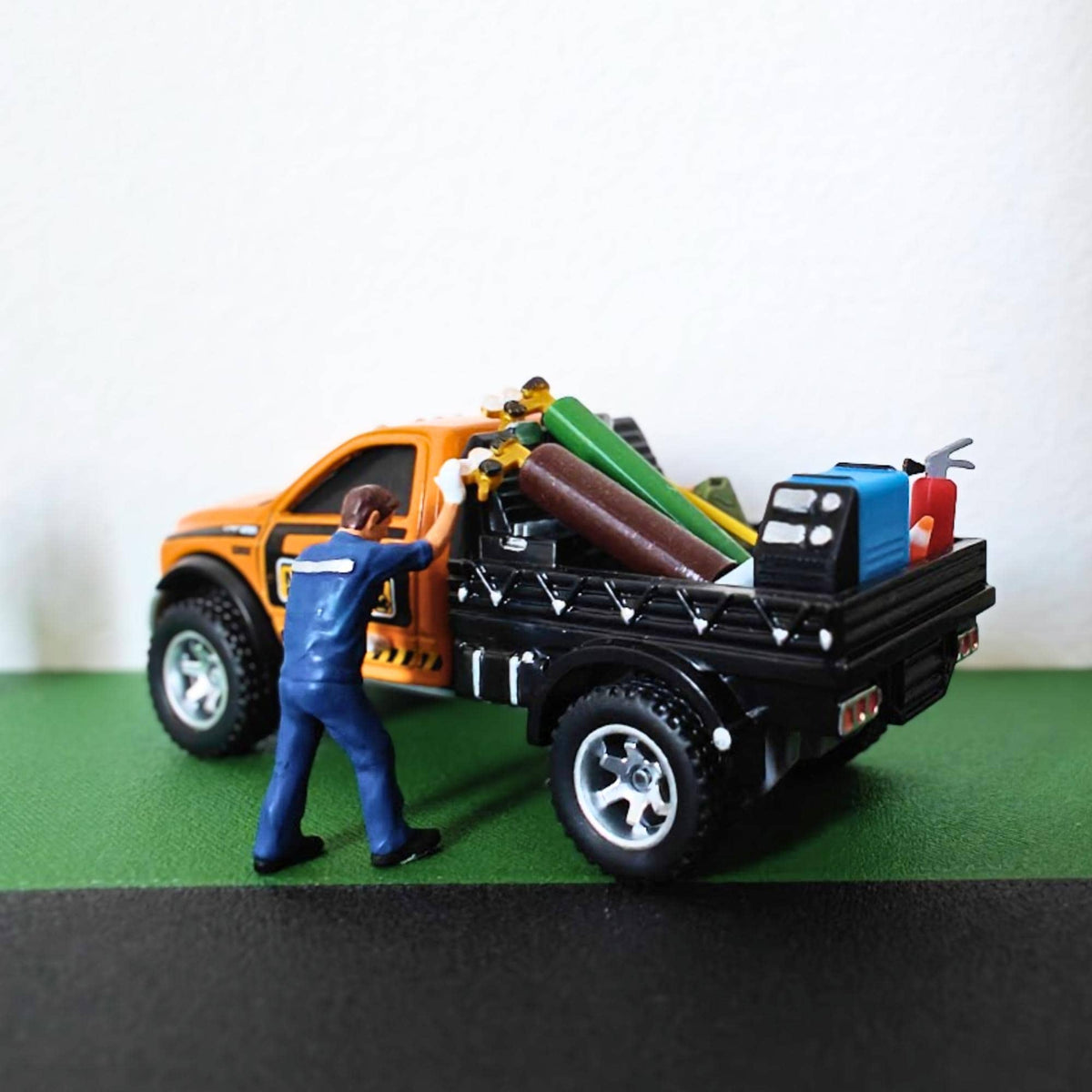 Model pickup truck carrying miniature gas cylinders and workshop equipment in the truck bed.