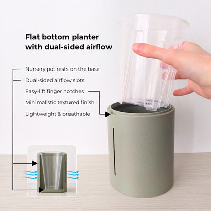 Sage flat-bottom planter with airflow openings and a clear nursery pot resting directly on the solid base.