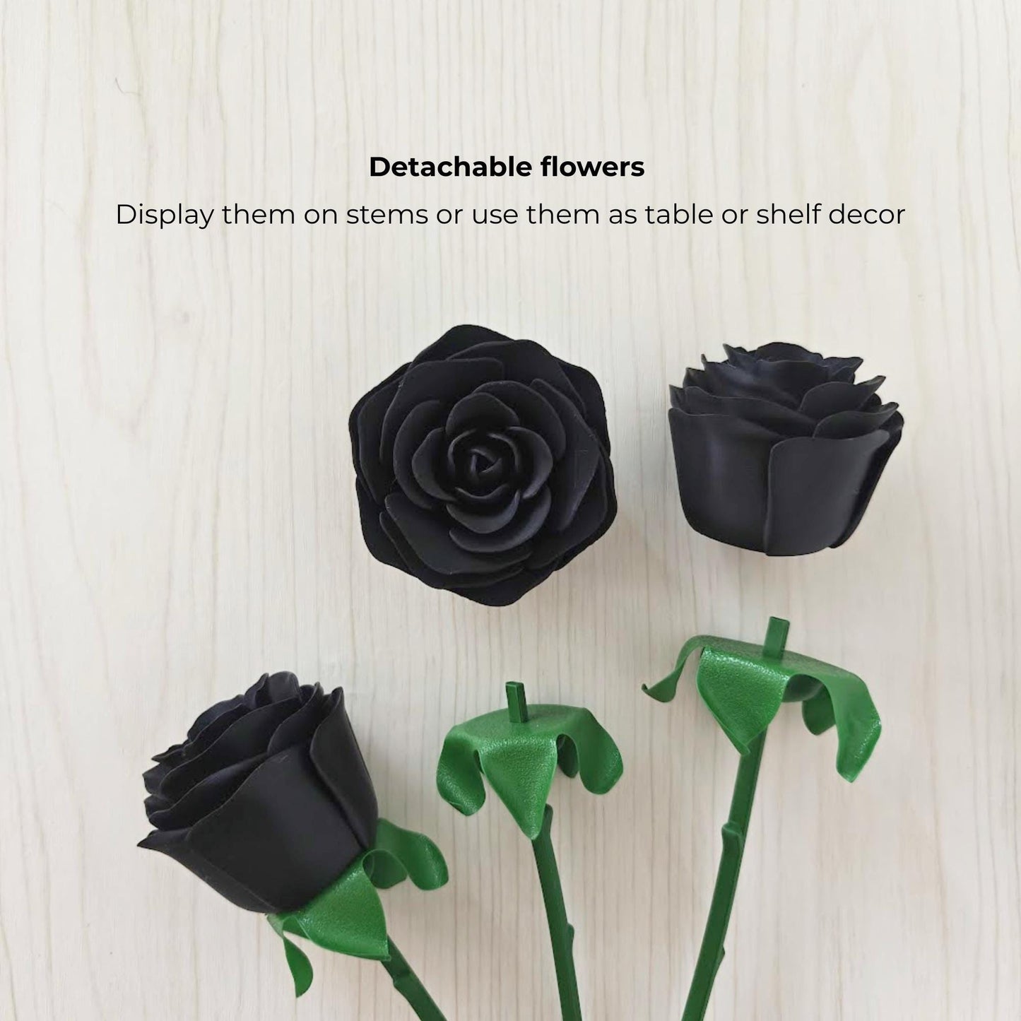 Detachable black rose heads shown separately from their green stems and leaf-shaped bases.