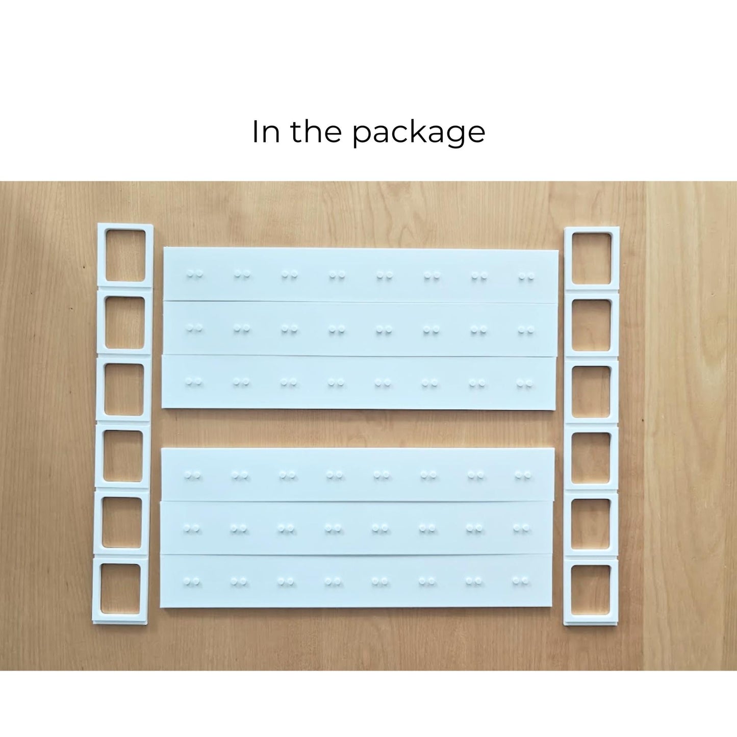 Modular white display-grid components laid out before assembly, including shelf sections and side supports.